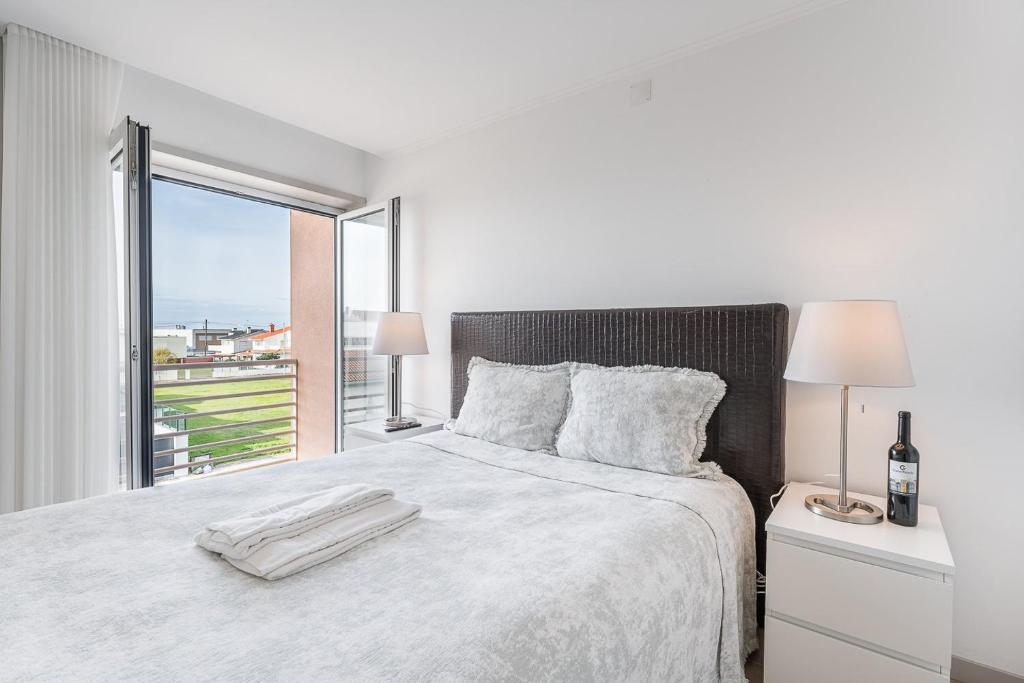 um quarto branco com uma cama grande e uma janela em GuestReady - Vacation family home near the beach em Esposende