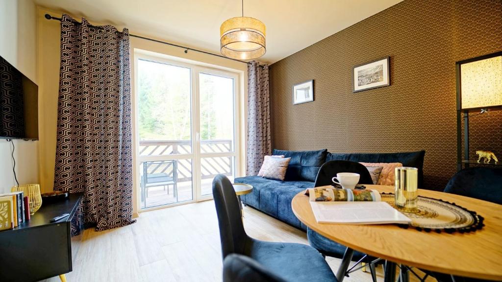 a living room with a blue couch and a table at Apartamenty Every Sky Szklarska Poręba, Żeromskiego 15c-5 in Szklarska Poręba