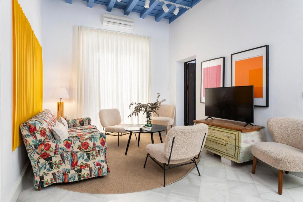 sala de estar con sofá y TV de pantalla plana en Magno Apartments Almirante Hoyos House, en Sevilla