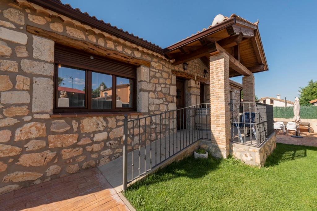 a stone house with a porch and a balcony at Casa Entre Hoces810paxJardín y barbacoa in Fuentemizarra
