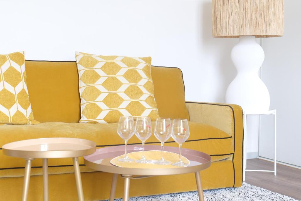 a yellow couch with two tables with wine glasses on it at Bel appartement idéalement situé centre-ville Angers in Angers