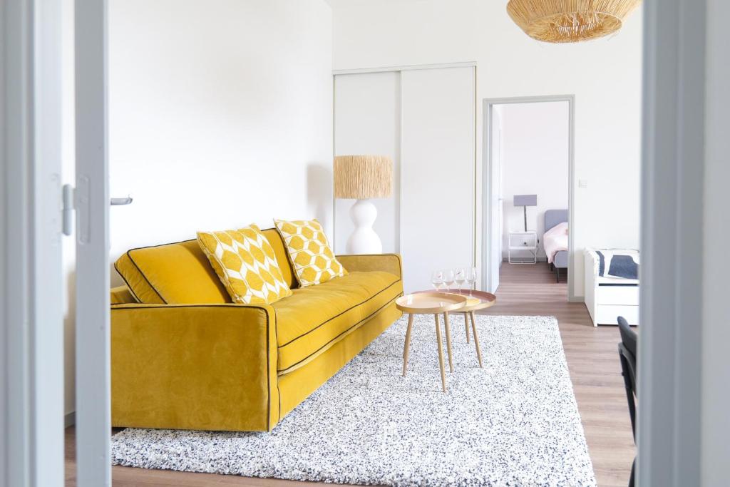 un salon avec un canapé jaune et une table dans l'établissement Bel appartement idéalement situé centre-ville Angers, à Angers