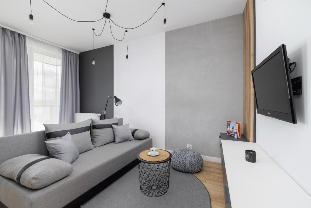 uma sala de estar com um sofá e uma televisão em Black and Grey Apartment in Cracow with Balcony, Parking and Desk by Renters em Cracóvia