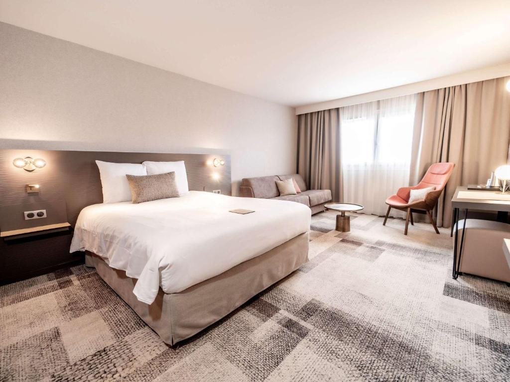 ボルドーにあるメルキュール ボルドー ラックの大きなベッドとデスクが備わるホテルルームです。