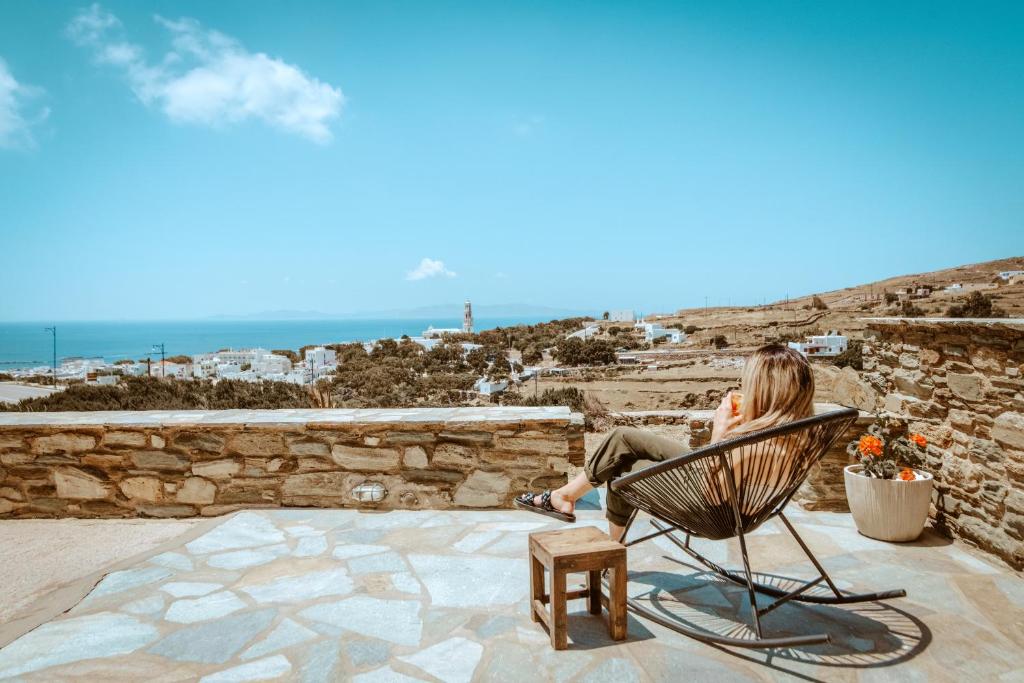 Enea by TinosHost في تينوس تاون: امرأة تجلس على كرسي وتطل على المحيط