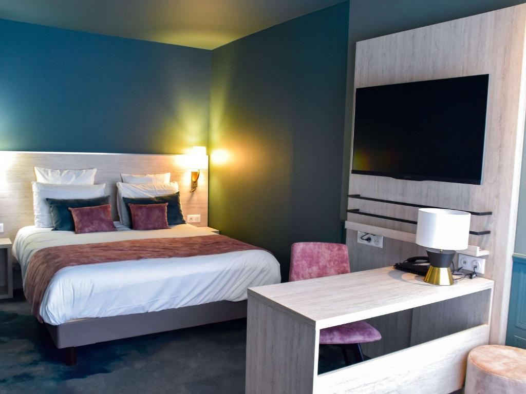 a hotel room with a bed and a desk with a tv at Hôtel Mercure Lyon Centre Charpennes Parc de la Tête d'Or in Villeurbanne
