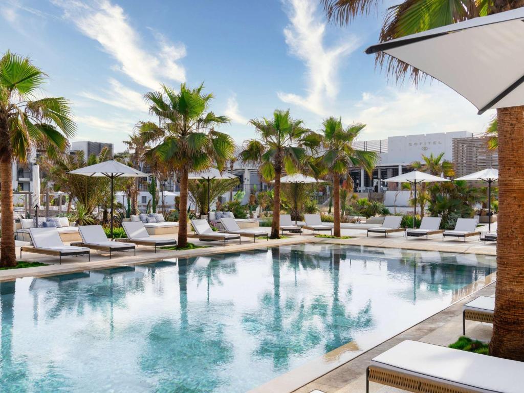 an infinity pool with lounge chairs and palm trees at Hotel Sofitel Agadir Thalassa Sea & Spa in Agadir