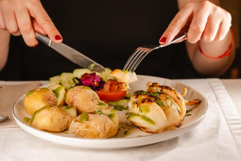 a person eating a plate of food with a fork and knife at Tamahuche Hotel Rural in Vallehermoso