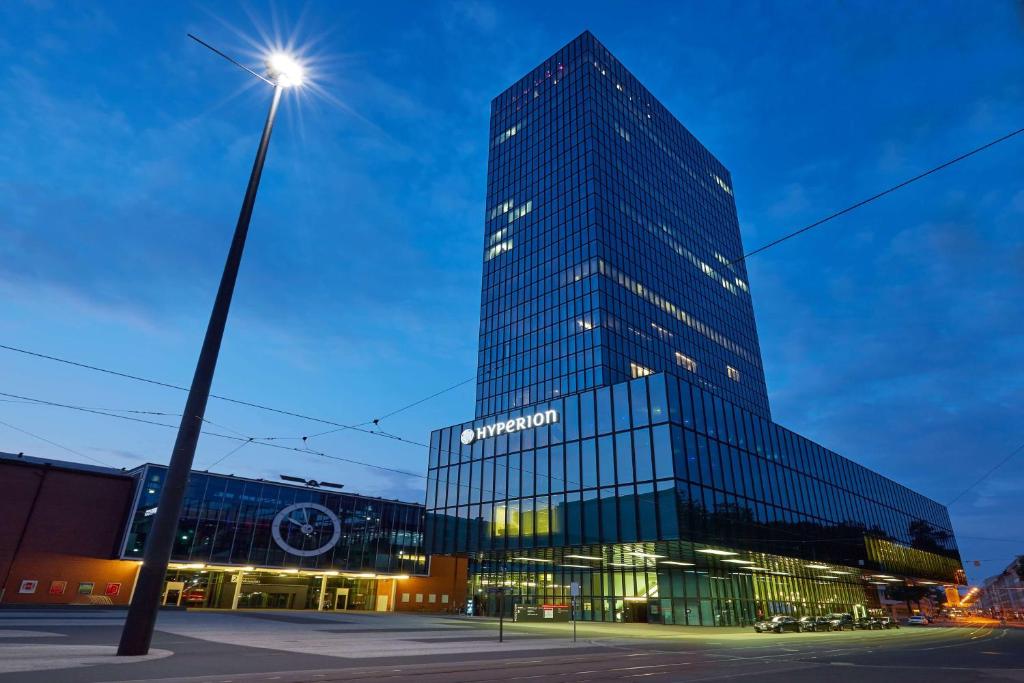 un edificio alto con un poste de luz delante de él en HYPERION Hotel Basel, en Basilea
