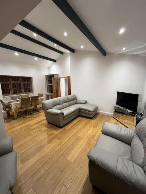 uma sala de estar com sofás e uma televisão de ecrã plano em The Forest Haven Cottage - Free Parking & Wi-Fi em Whitefield