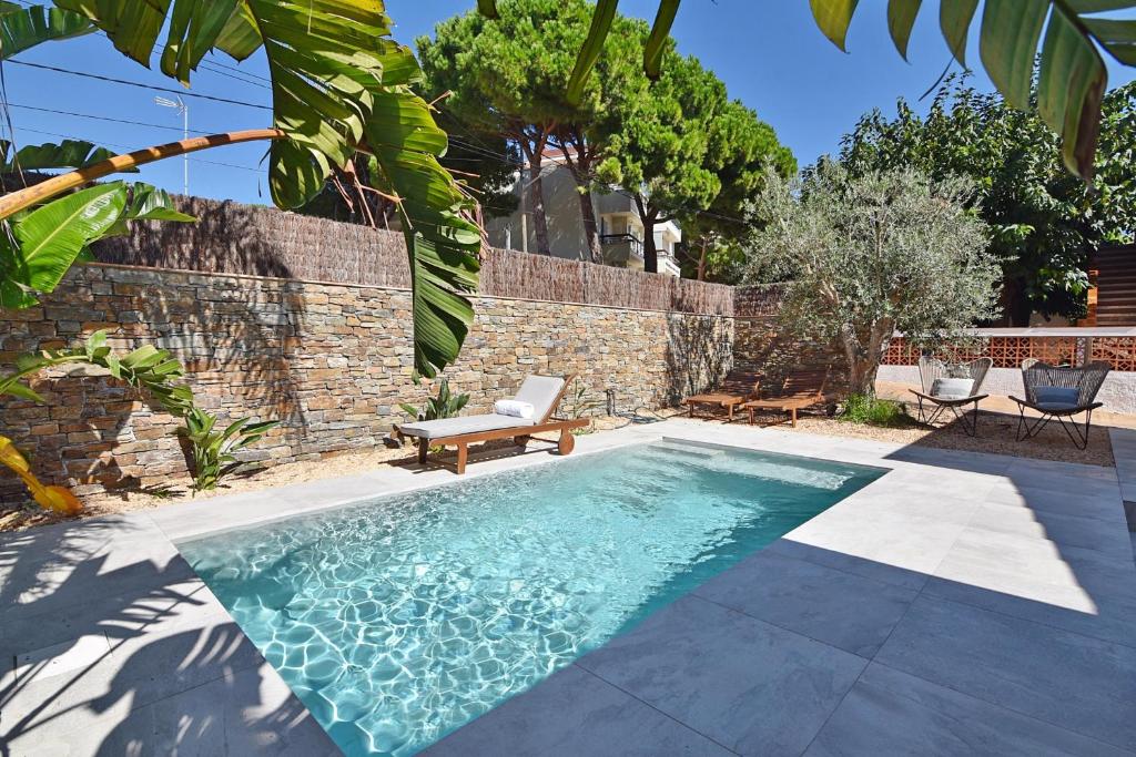 uma piscina com um banco e uma cadeira num quintal em Villa Montgo 2 em L'Escala