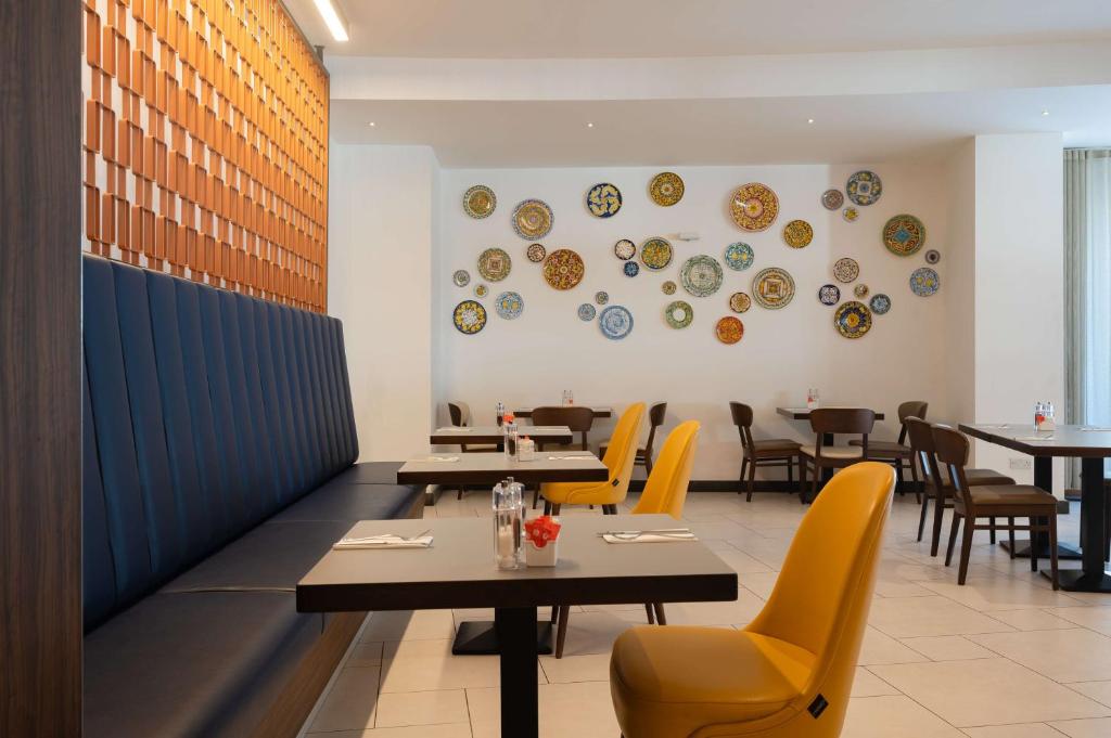 a restaurant with tables and chairs and plates on the wall at DoubleTree by Hilton Malta in St Paul's Bay