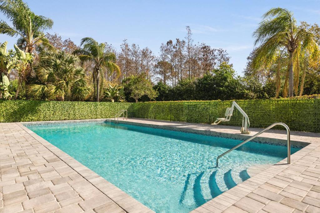 a swimming pool in a yard with a hedge at Spark by Hilton Orlando Universal Blvd in Orlando