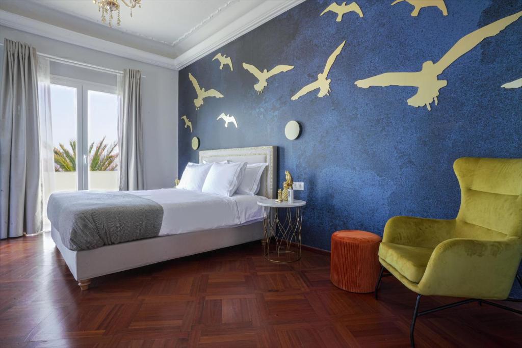 a bedroom with a bed and birds on a blue wall at Pafsilipon Suites in Ermoupoli