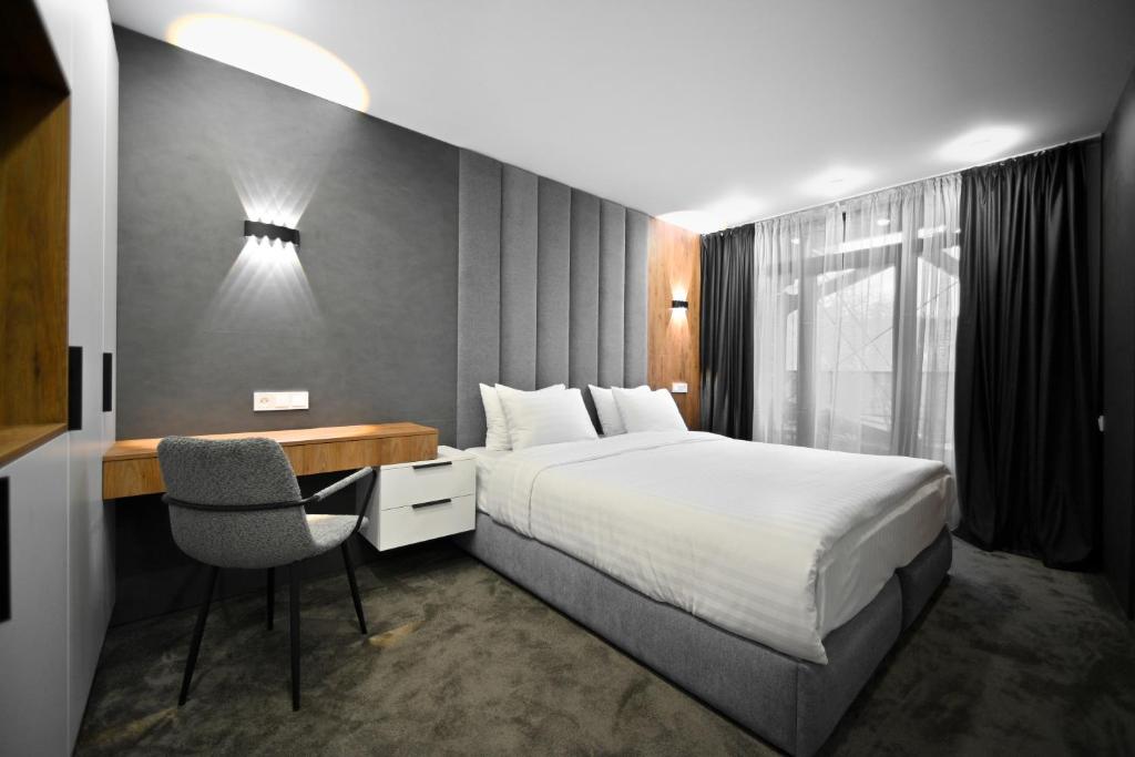a bedroom with a bed and a desk with a chair at London Hotel Yerevan in Yerevan