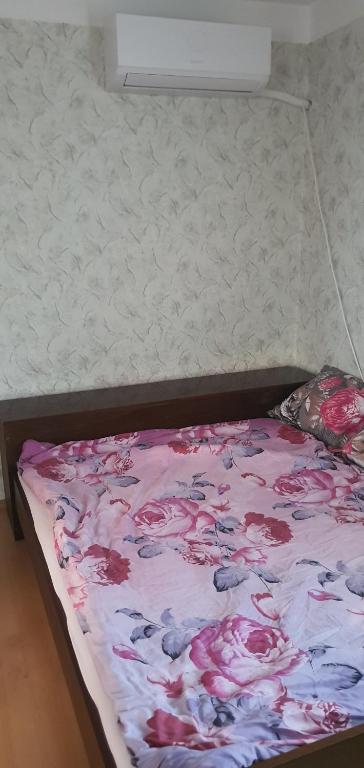 a bed with a floral blanket on top of it at Къща за гости in Razgrad