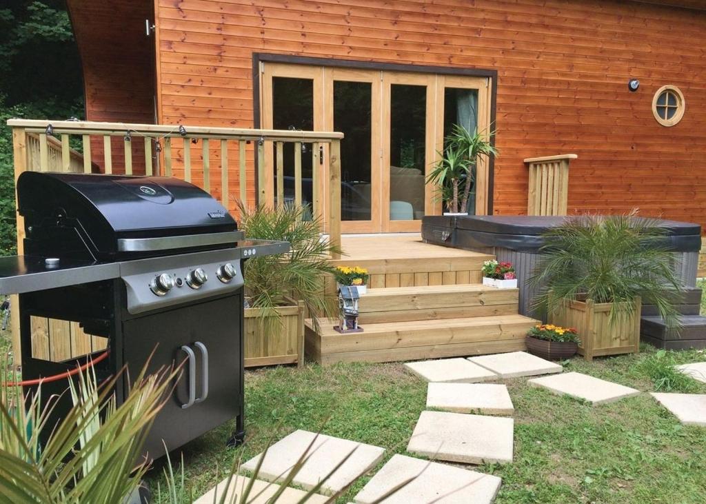 a backyard with a grill and a house at Herons Lake Retreat in Caerwys
