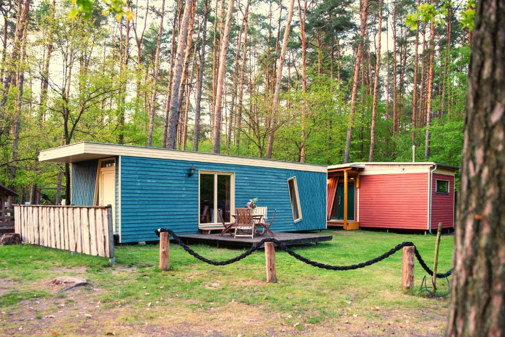 una casa azul con porche y casa roja en Knatter(ferien)häuschen, en Bantikow