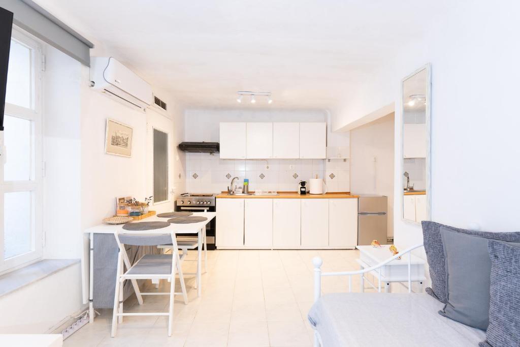 a kitchen with white cabinets and a table and chairs at Syros DouBleTS rooms in Ermoupoli
