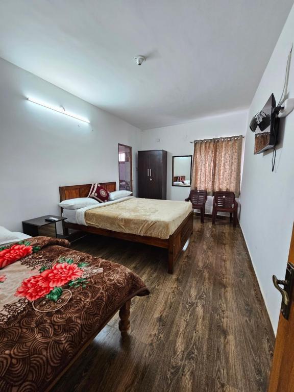 a hotel room with two beds and a television at Happy Home Stay in Ooty