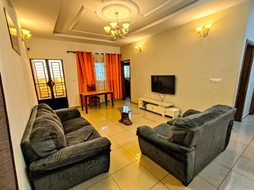 uma sala de estar com dois sofás e uma televisão em Résidence D em Bafoussam