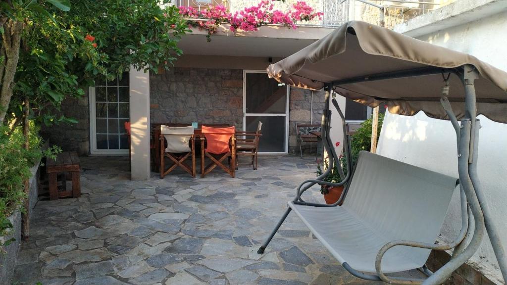 a chair under an umbrella on a patio at Stone home Lyhna in Líkhna