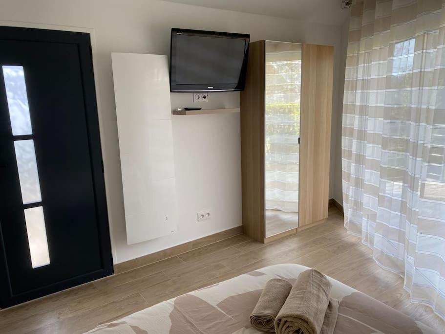 a bedroom with a bed with a tv on the wall at Studio Les Oliviers in Noisy-le-Grand