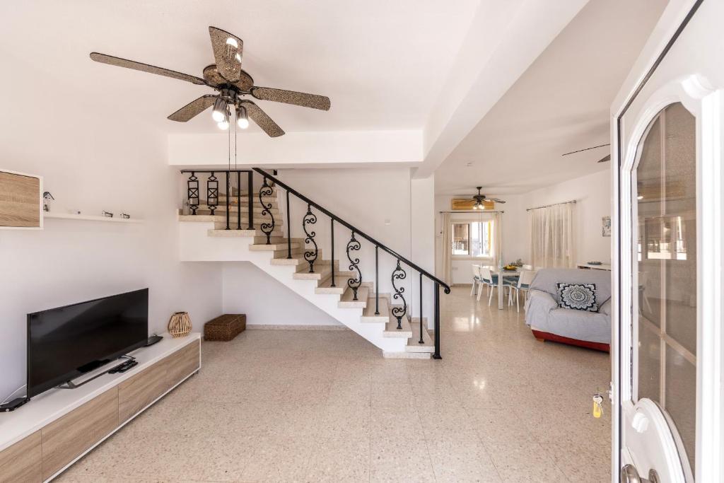 a living room with a staircase and a ceiling fan at Ayia Thekla Sea Breeze Villa in Ayia Napa