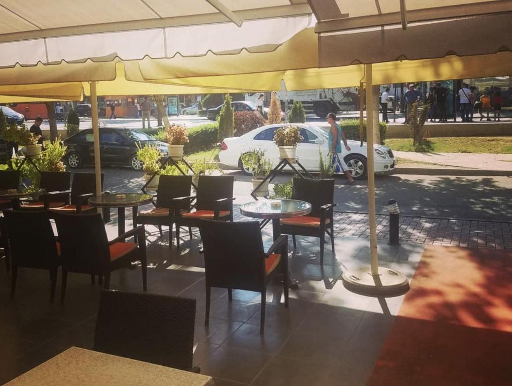 un restaurante con mesas y sillas bajo sombrillas en Hotel Kombinat en Tirana