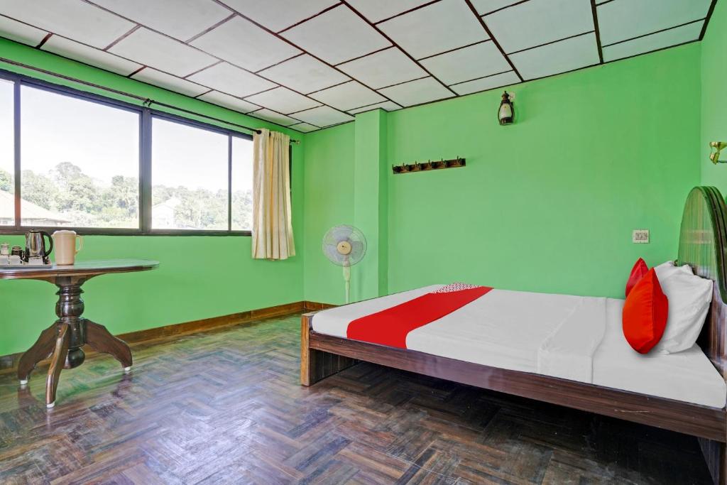 Habitación verde con cama y mesa en Flagship Green Fort Thekkady, en Thekkady