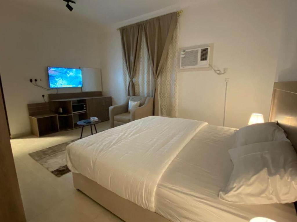 um quarto com uma cama branca e uma televisão em نايتس للوحدات المفروشة em Tabuk