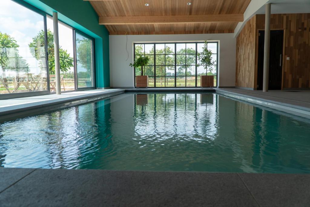 uma piscina vazia com paredes verdes e janelas em Vakantiewoning de Worfthoeve em Geel