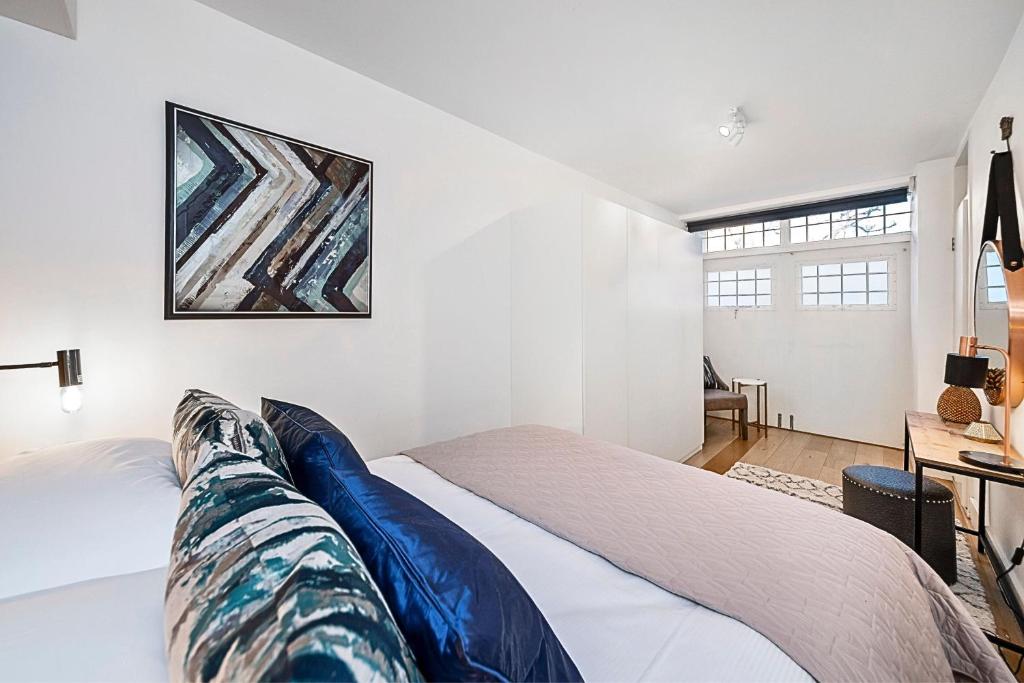 a bedroom with a bed and a painting on the wall at Kensington Oasis Central London 2BR Private House - Near Harrods, Kensington Palace, and other London Attractions in London