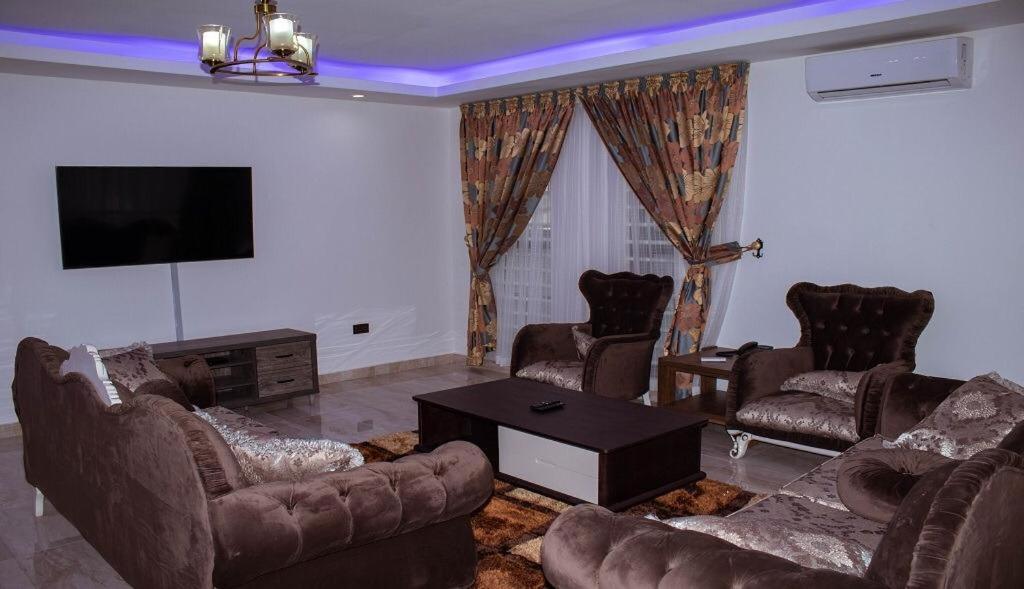 a living room with leather furniture and a flat screen tv at Luxe Isle by Harolty, East Legon in Accra