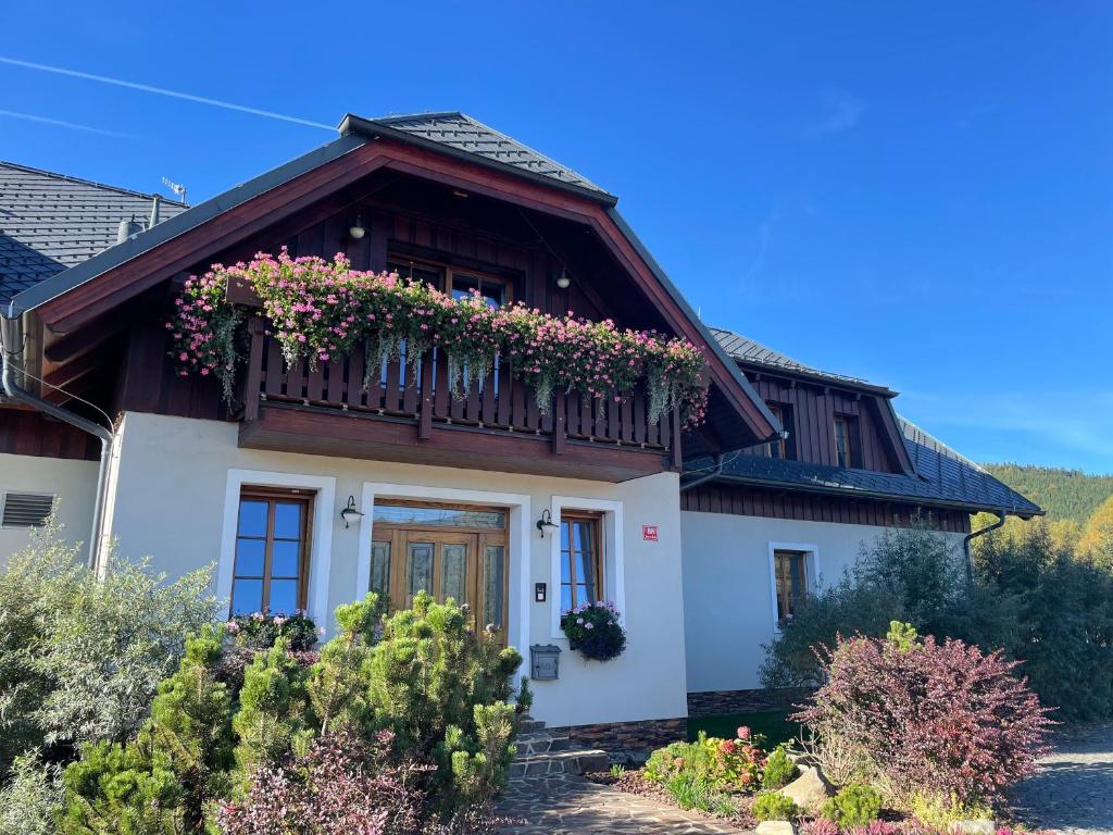 a house with a balcony with flowers on it at Wellness Penzion Gabreta in Borová Lada