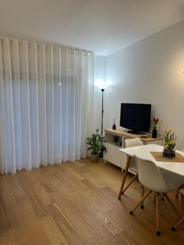 a living room with white curtains and a table and a television at A Casa di Gioia in Castel di Sangro