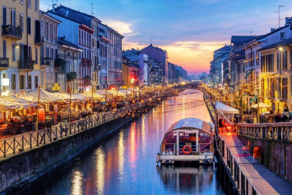 a river with boats in a city at dusk at Apartment Navigli Milano in Milan