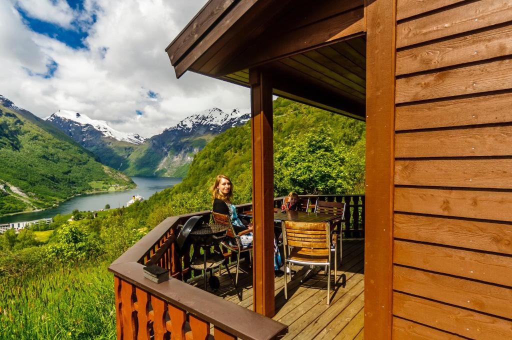 a woman sitting on a deck with a view of a mountain at FOSSEN CAMPING in Geiranger