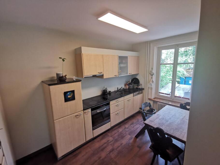 cocina con armarios de madera, mesa y ventana en Beautiful central Apartment, en Berna