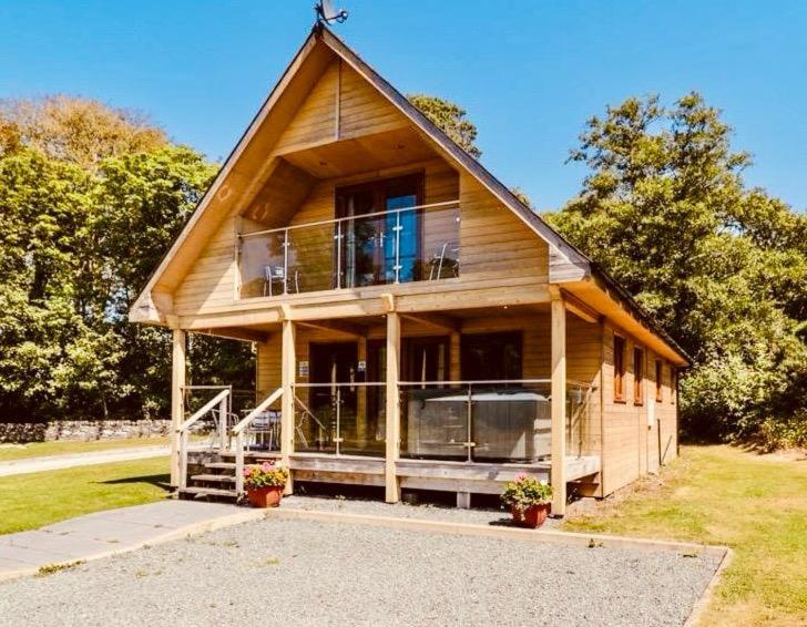 a large wooden house with a large balcony at Artro Lodge Luxury 3 Bedroom, 3 Bathroom & Hot Tub in Llanbedr