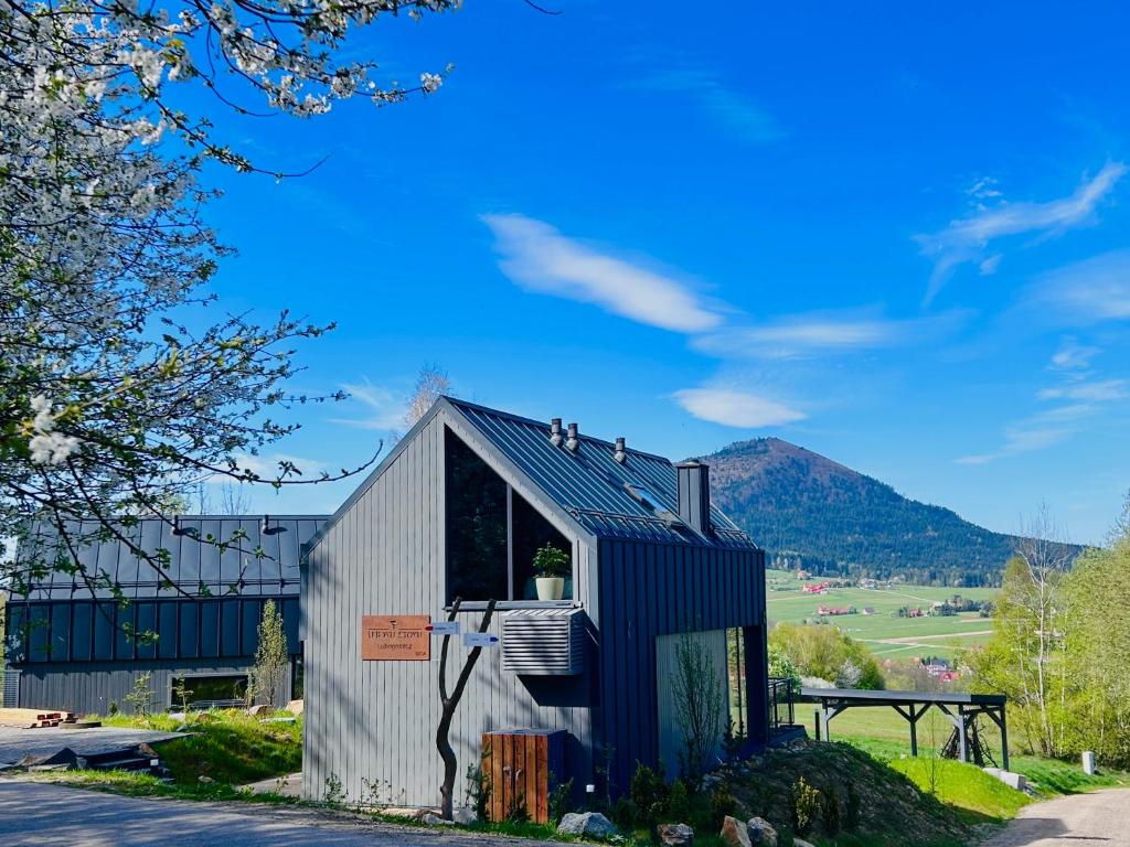 a small black and white building with mountains in the background at U Boku Stoku in Kasina Wielka