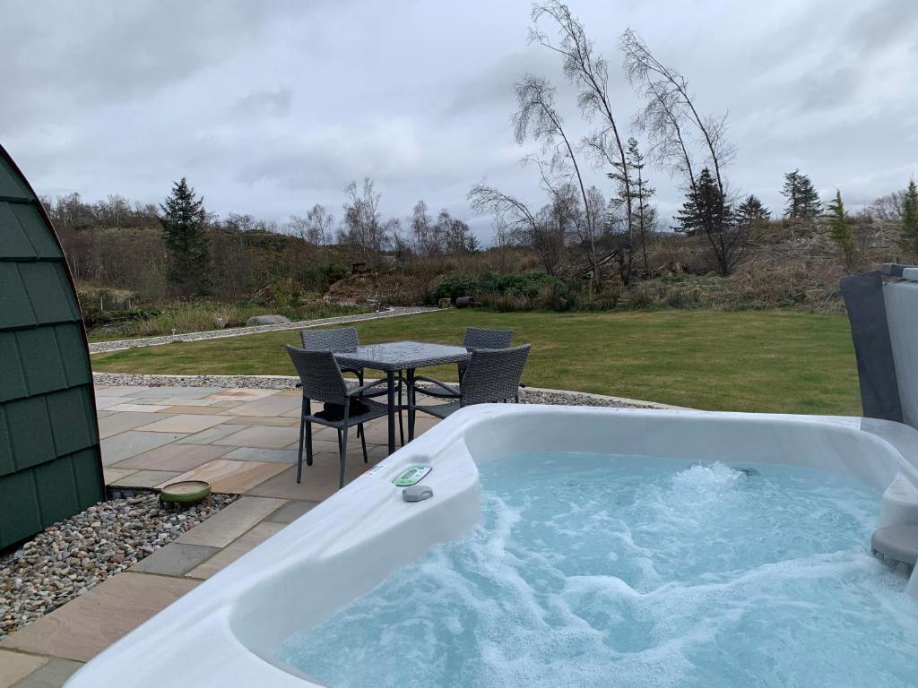 a jacuzzi tub in a yard with a table at Tawny Owl Pod with Hot Tub in Oban