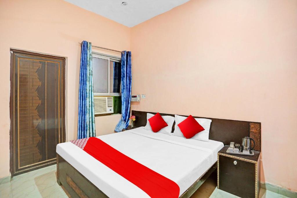 1 dormitorio con 1 cama grande con almohadas rojas en Flagship Hotel Status en Bareilly