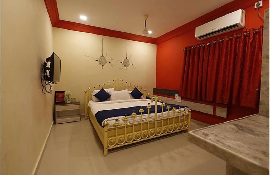 a bedroom with a bed and a red wall at Hotel Suraj Inn in Surat