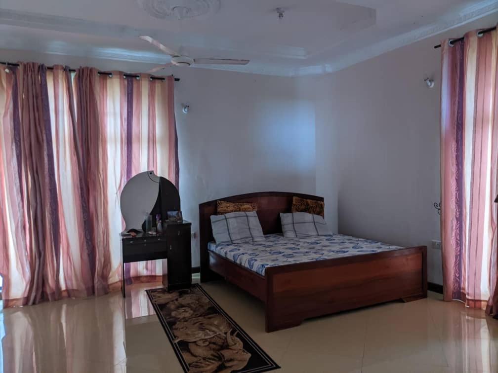 ein Schlafzimmer mit einem Bett in einem Zimmer mit Vorhängen in der Unterkunft Mjengoni in Daressalam