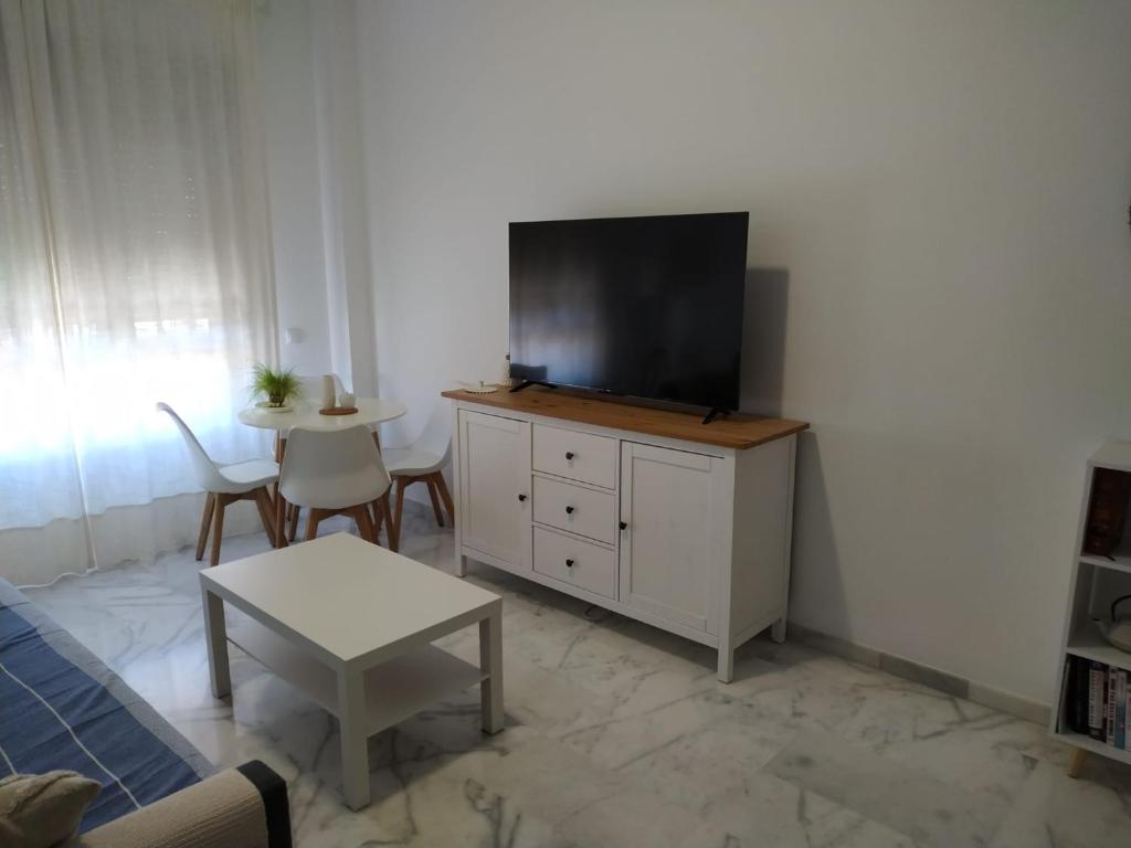 Apartamento en Lux Bormujos في بورموخوس: غرفة معيشة مع تلفزيون بشاشة مسطحة على خزانة