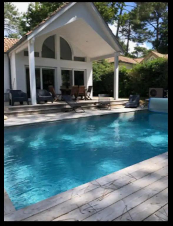 une piscine devant une maison dans l'établissement Villa DUNE, à Biscarrosse