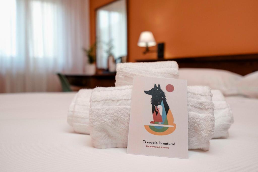 una pila de toallas con un cartel en la cama en Hotel Altevie en Guardiagrele