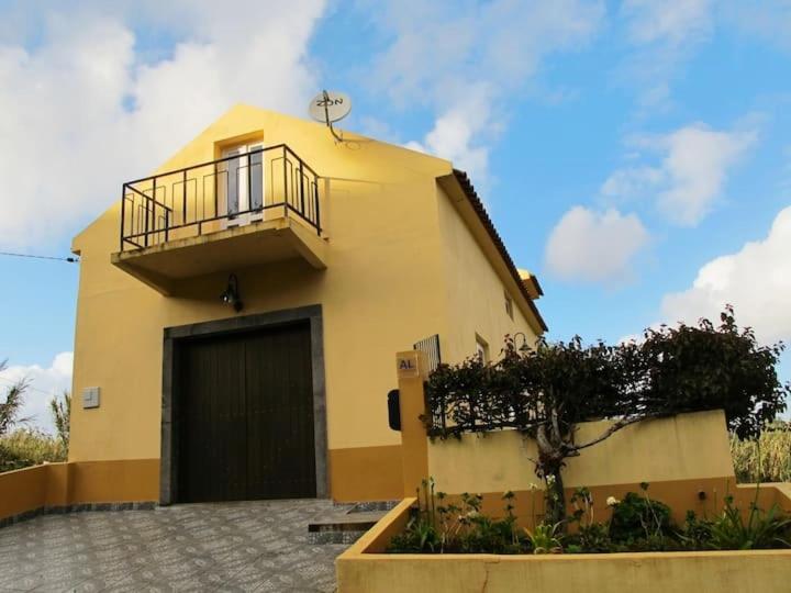 een geel huis met een balkon erboven bij GuestReady - Casa do Bisbis in Lanceiros