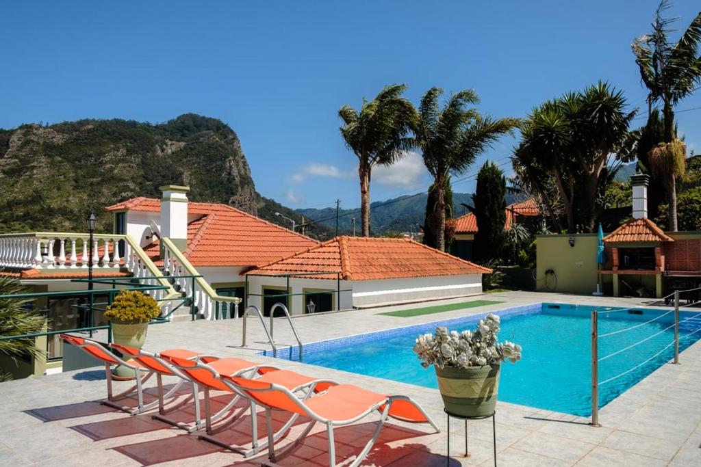 a swimming pool with chairs next to a house at GuestReady - Hikers Haven in Faial